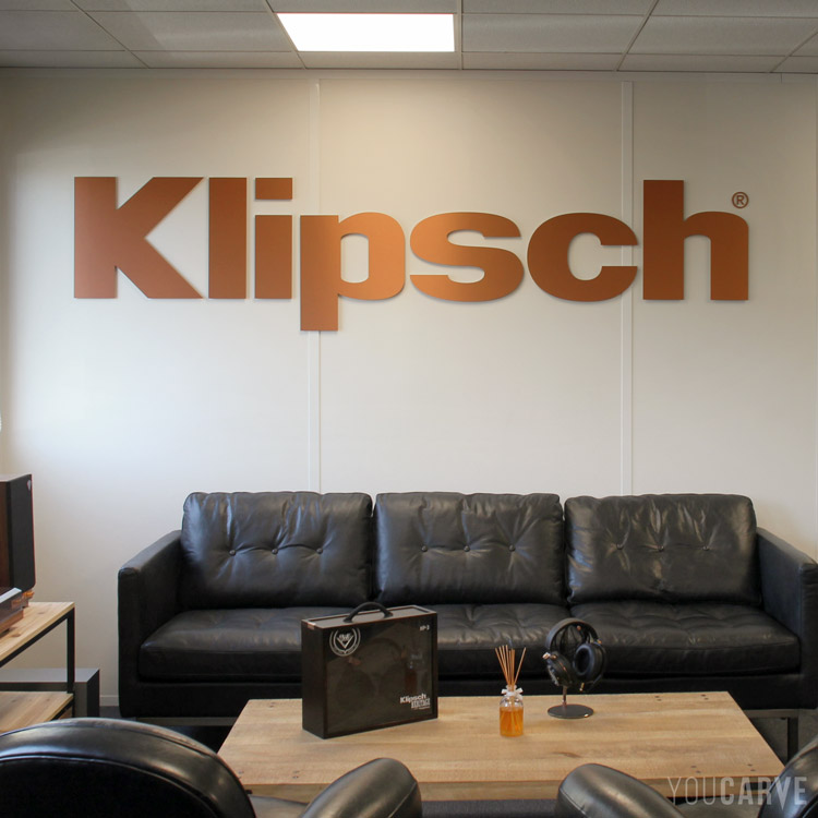 Enseigne intérieure, décoration salle d'accueil Klipsch France, logo découpé sur mesure en dibond-aluminium cuivré brossé, fixation murale avec mousse double-face.