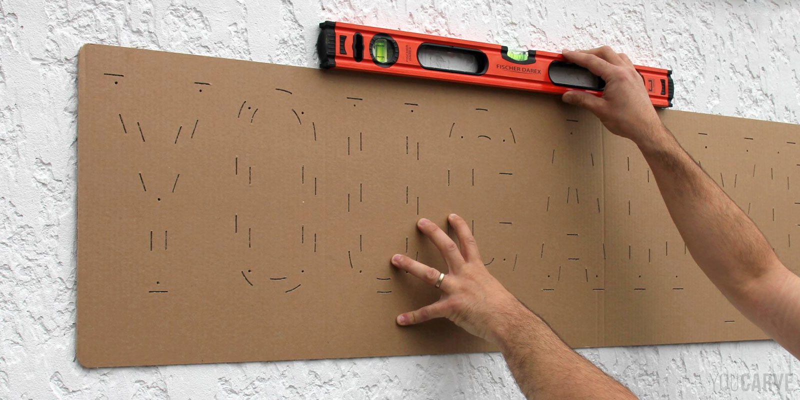 Installation enseigne - Etape 1a - Positionnement du gabarit de perçage Centrage et positionnement à l'horizontale du gabarit de perçage en carton, avec un niveau de bulle