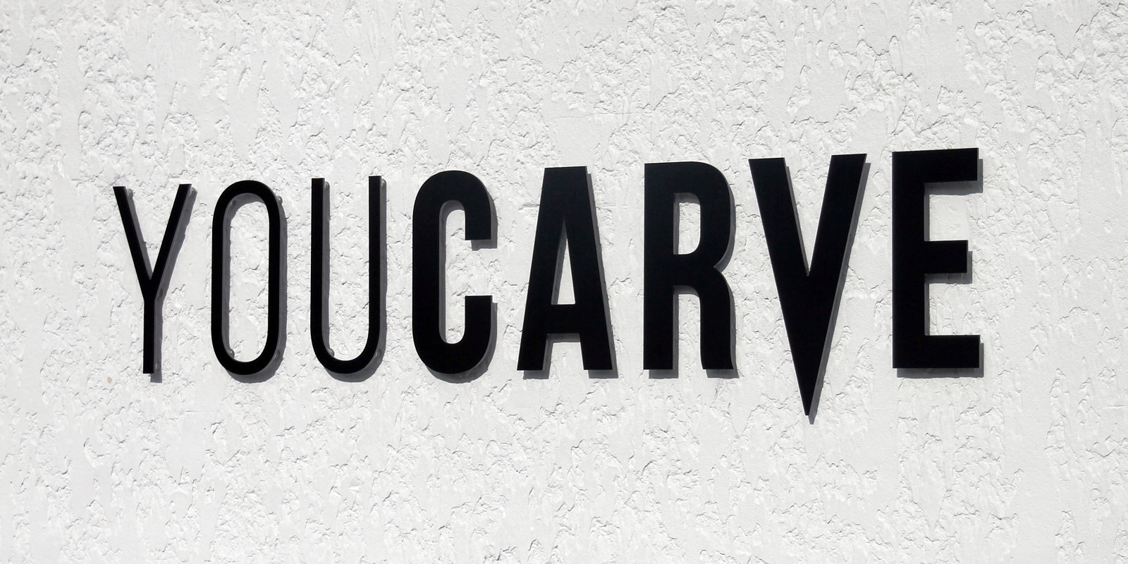 Installation enseigne - Etape 5 - Résultat final enseigne lettres dibond fixées sur entretoises clipsables Enseigne YOUCARVE réalisées en lettres dibond noir fixées sur entretoises clipsables (douilles d'écartement)