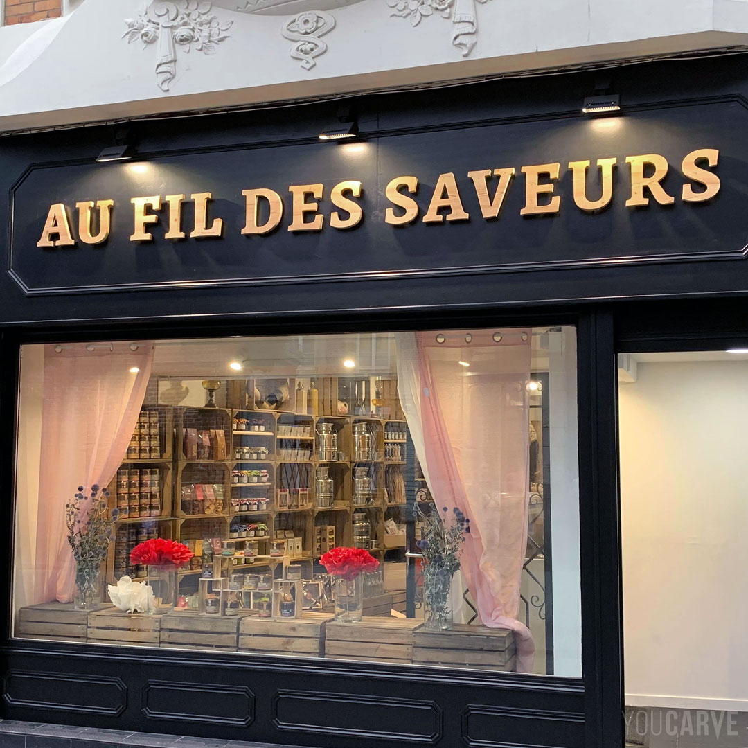 Réalisé par Au Fil des Saveurs : enseigne épicerie à Arras, lettres découpées en bois (mélèze épaisseur 26 mm), fixation sur entretoises avec gabarit de perçage.