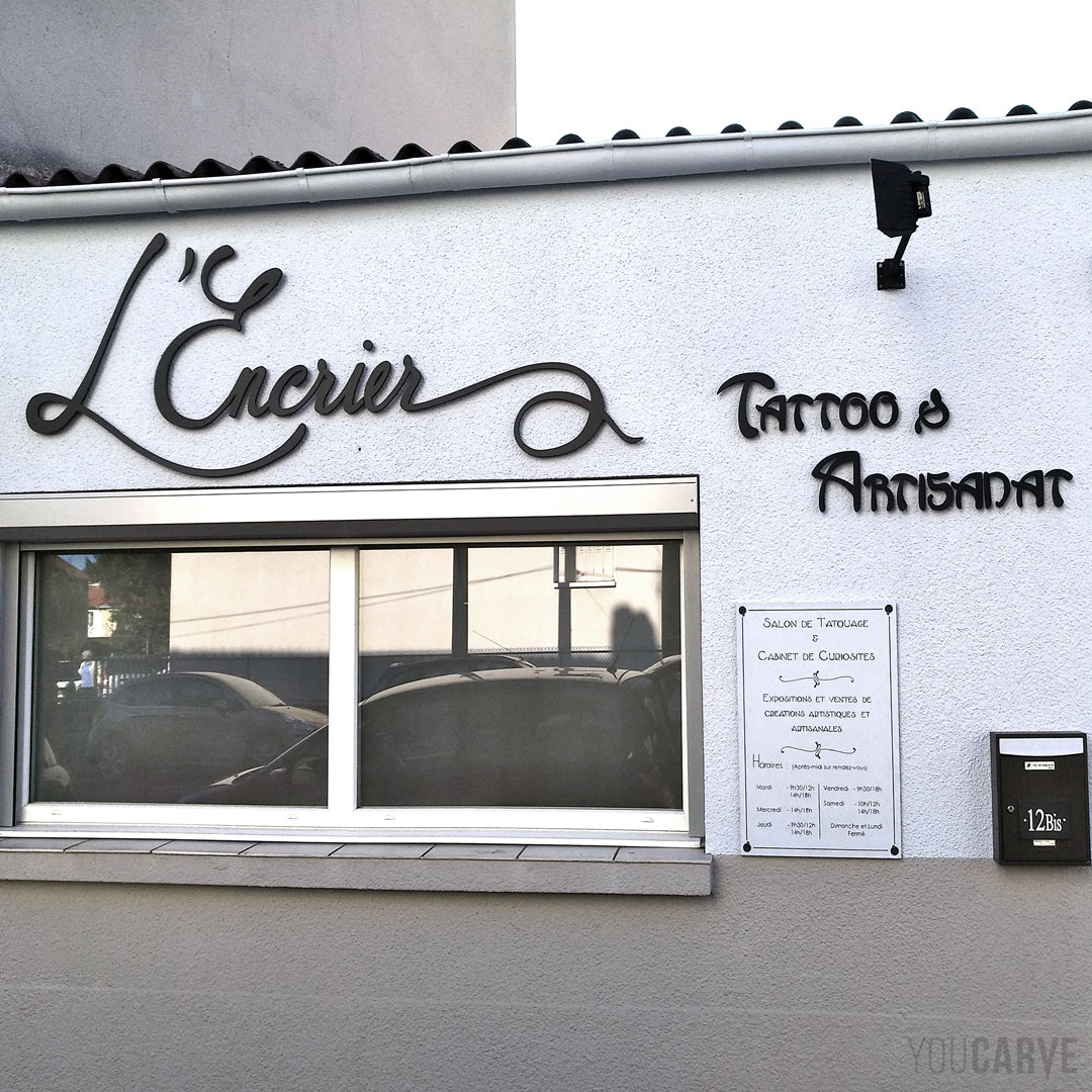 Réalisé par L'Encrier : enseigne salon de tatouage à Aubière, lettres et logo fabriqués sur-mesure en PVC expansé noir épaisseur 10 mm, fixation sur entretoises avec gabarit de perçage.