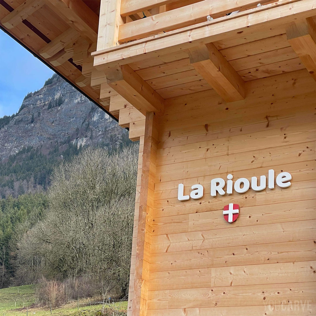 Réalisé par La Rioule : enseigne d’un chalet en Haute-Savoie, lettres et croix de Savoie découpées en PVC expansé blanc épaisseur 19 mm + alu-dibond laqué rouge, fixation sur entretoises avec gabarit de perçage.