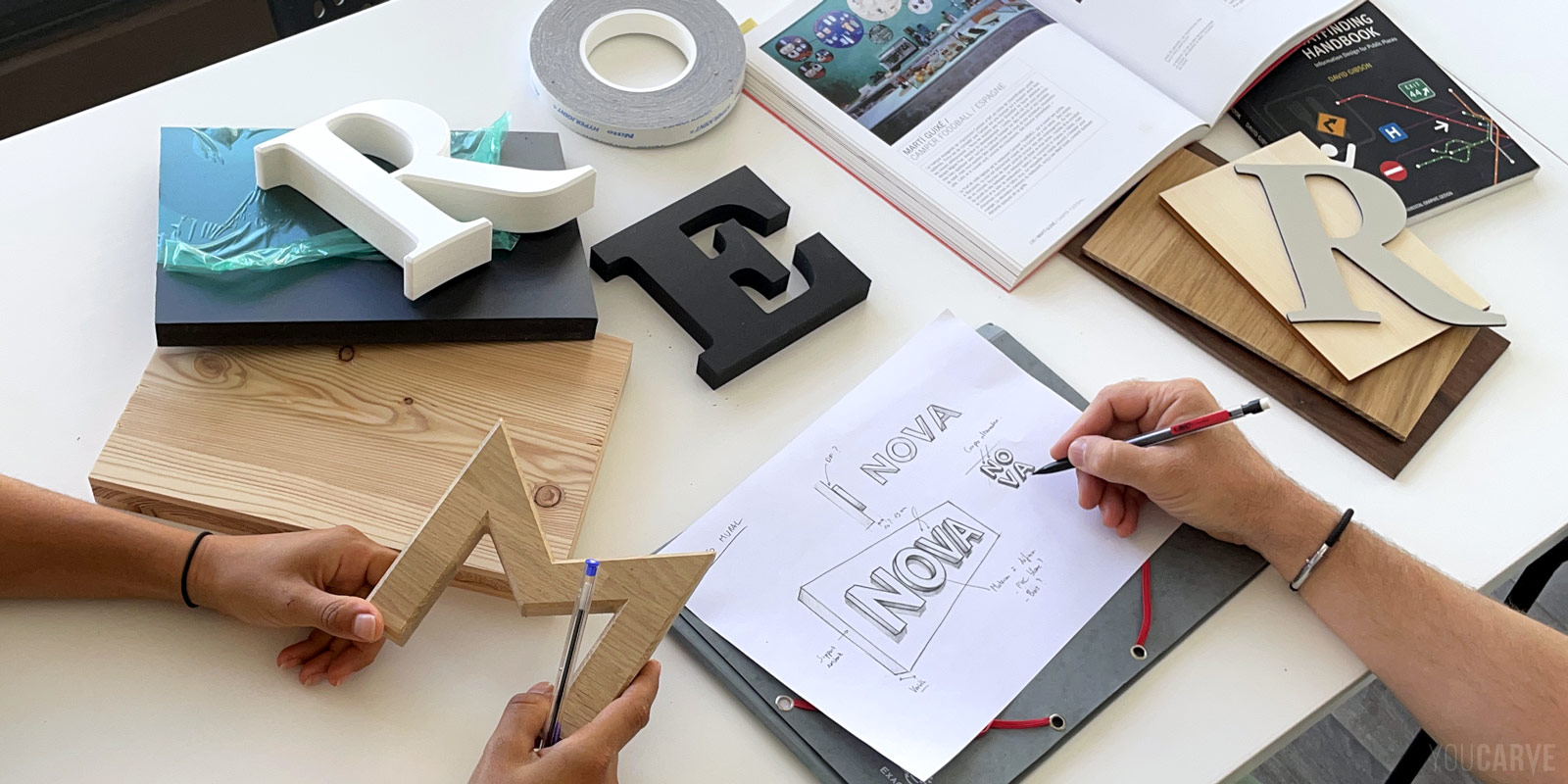 Enseigne ou logo mural : la conception en amont par le designer, l’architecte ou le décorateur Photo d’une table au cours d’une réunion de travail menée par le designer ou le décorateur, avec des croquis et des échantillons de différents matériaux