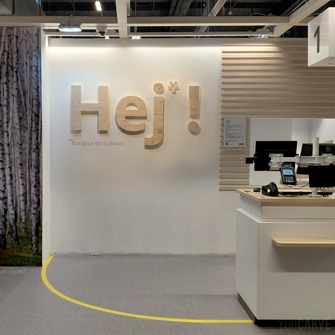 Ikea Lille - Logo mural 'Hej' en bois (épicéa) Logo mural "Hej" découpé en bois (épicéa) pour la décoration de caisses Ikea à Lille