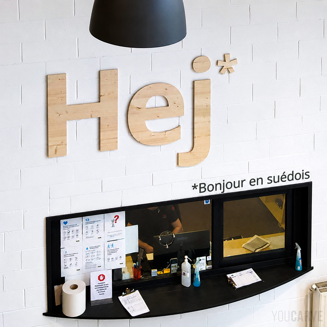 Ikea Lomme - Logo mural 'Hej' en bois (épicéa) Logo mural "Hej" découpé en bois (épicéa) pour la décoration du service client d’Ikea à Lomme